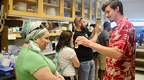 Former graduate student Jack Conroy shows a jar of preserved zooplankton to a public tour attendee.