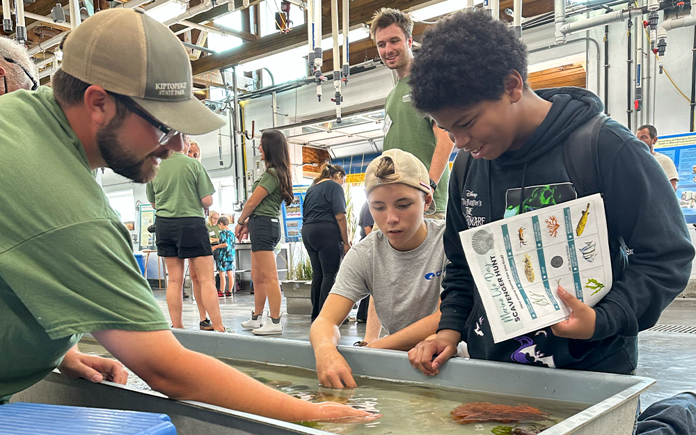 VIMS ESL Lab and Research Specialist Guy Sayers helps two young attendees get hands-on with marine life. Photo by Ethan Smith.
