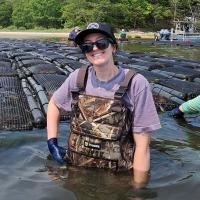 Healy Ealy-Whitfield, standing in the water surrounded by oyster baskets