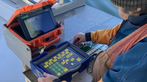 A scientist measures fish on an electronic measuring board, connected to a digital tablet